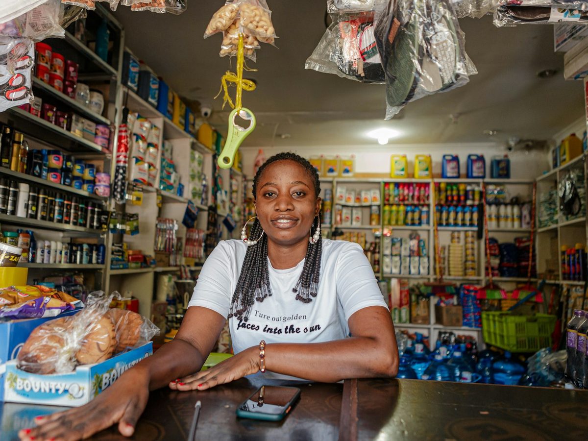A shop owner smiling behind the counter of her well-stocked store